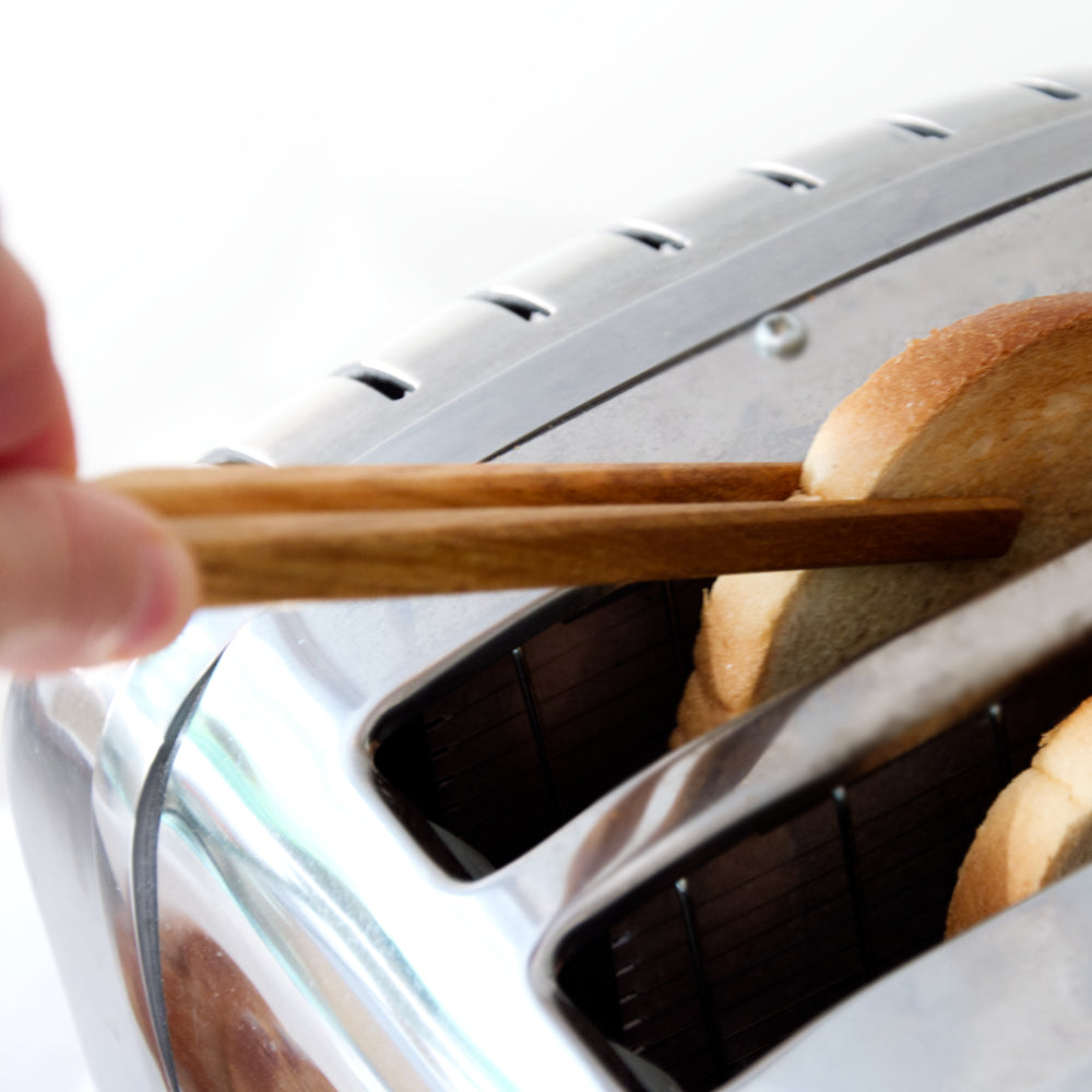 Toastzange greift nach Toastscheibe in Toaster Kirschholz